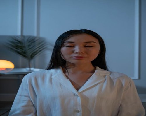 A person resting with closed eyes in a softly lit living room